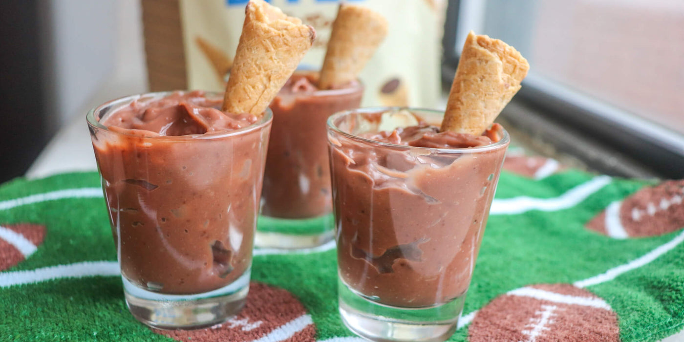 Close-up of pudding shots served on a table with a baseball-themed tablecloth.